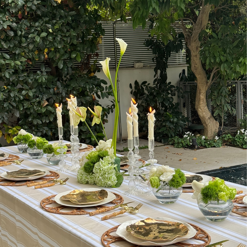   מארז סטיילינג להשכרה שולחן אירוח חגיגי עם מפת פסים בצבע בז לבן עם פלייסמט מקש חום צלחות זהב נרות לבנים גבוהים ופמוטי זכוכית  