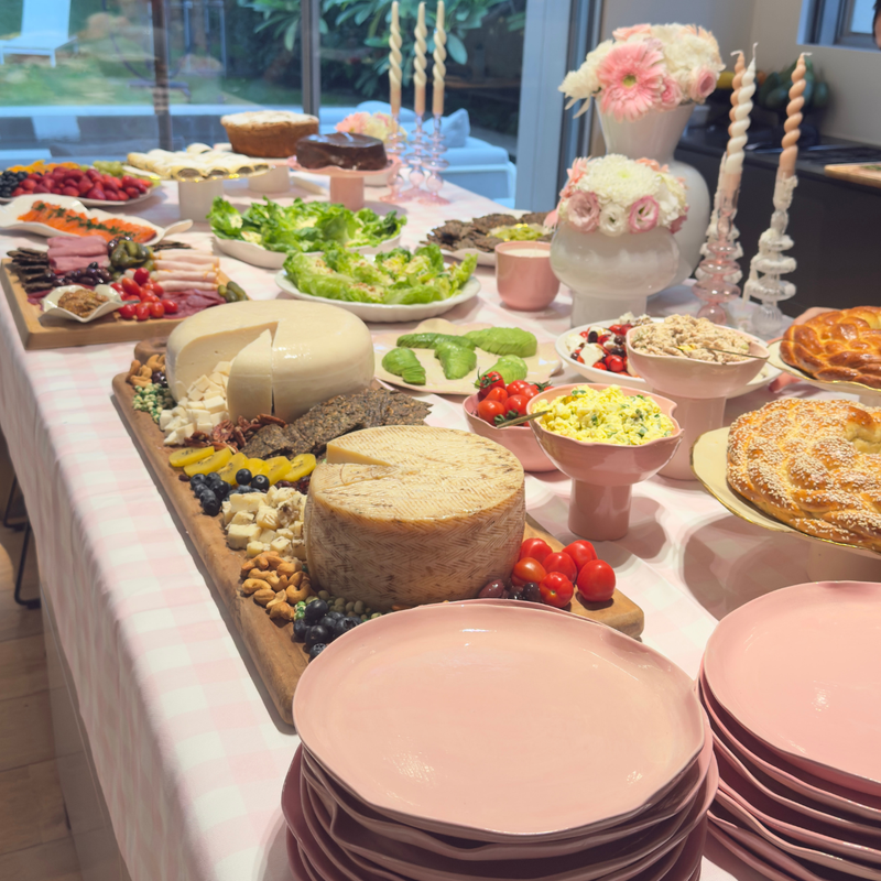 שולחן בופה מעוצב להשכרה בסגנון ורוד פסטל עם כלי הגשה ורודים, נרות ופרחים לאירוח